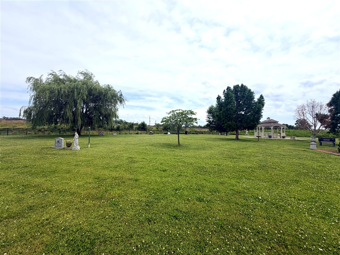 Open lawn and mature trees across the Forever Home Cemetery grounds